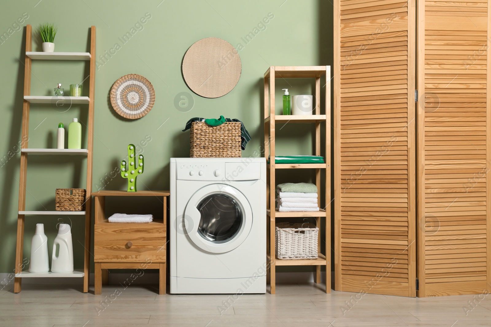 Photo of Washing machine, detergents and basket with laundry in room