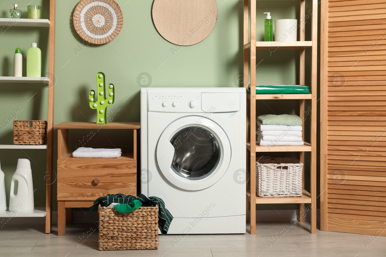 Photo of Washing machine, detergents and basket with laundry in room