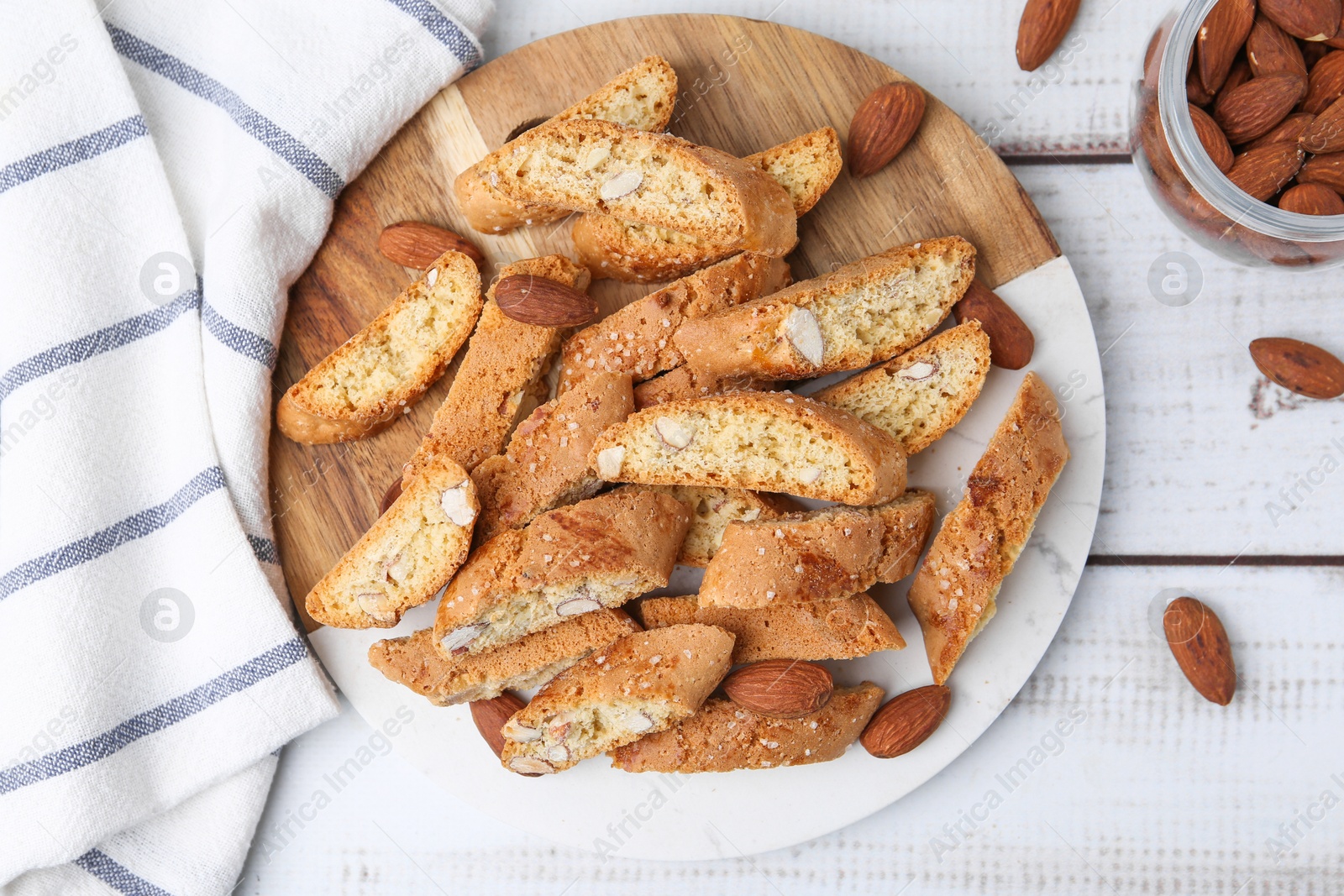 Photo of Tasty almond biscuits (Cantuccini) and nuts on light wooden table, flat lay