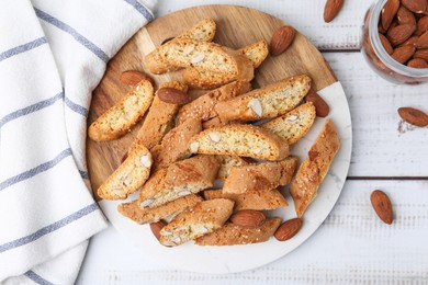 Photo of Tasty almond biscuits (Cantuccini) and nuts on light wooden table, flat lay