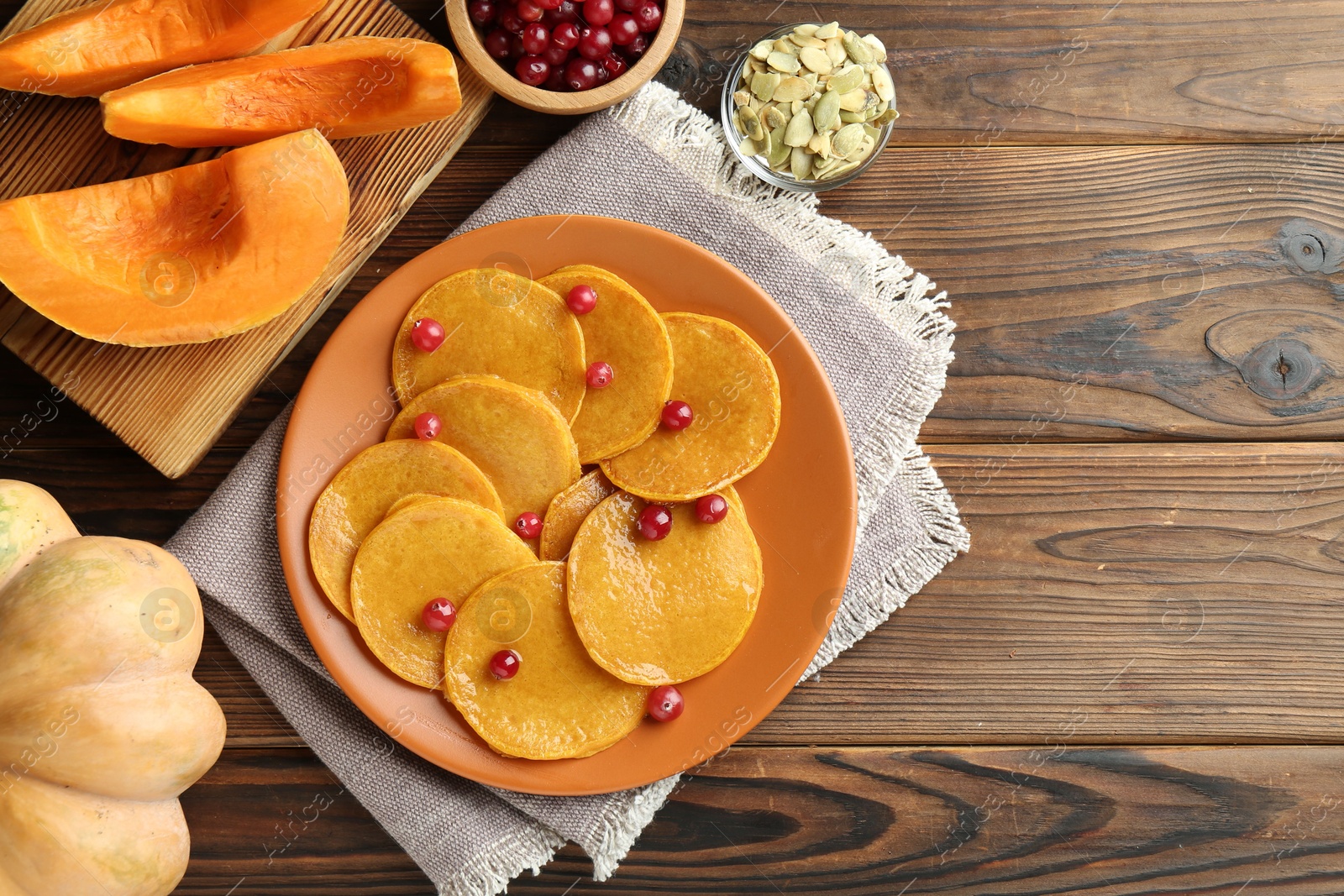 Photo of Tasty pumpkin pancakes with cranberries served on wooden table, flat lay. Space for text