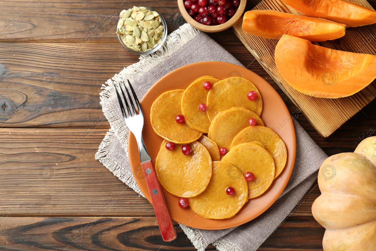 Photo of Tasty pumpkin pancakes with cranberries served on wooden table, flat lay. Space for text