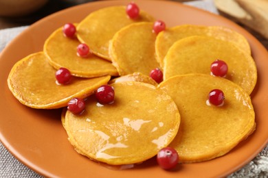 Photo of Tasty pumpkin pancakes with cranberries and honey on table, closeup