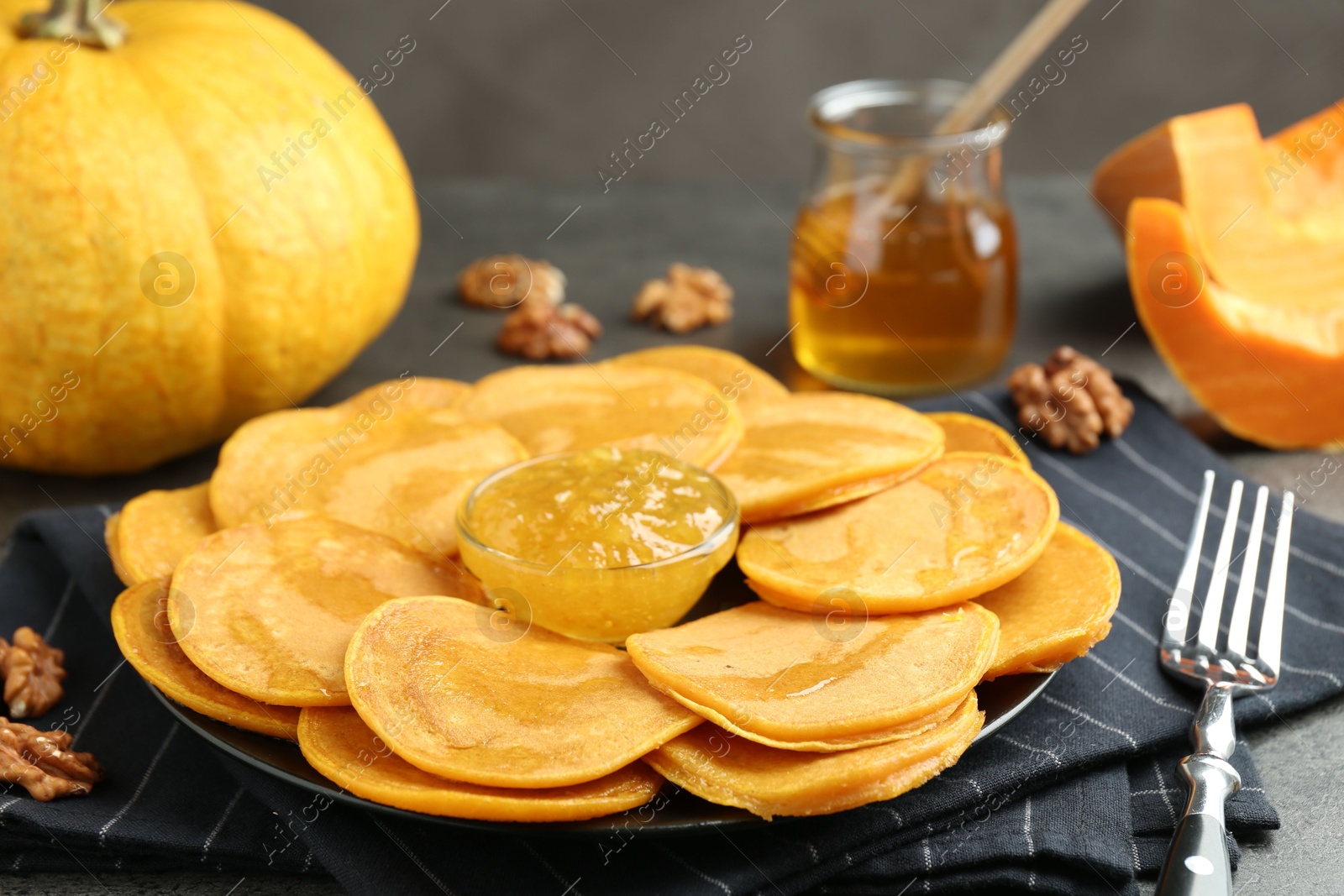 Photo of Tasty pumpkin pancakes with honey, walnuts and jam on table, closeup