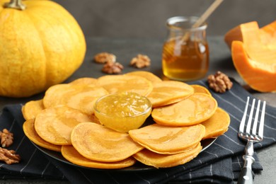 Photo of Tasty pumpkin pancakes with honey, walnuts and jam on table, closeup