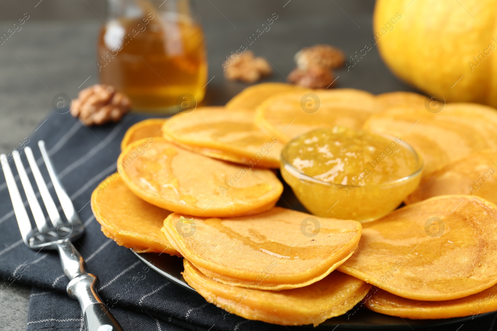 Photo of Tasty pumpkin pancakes with honey and jam on table, closeup