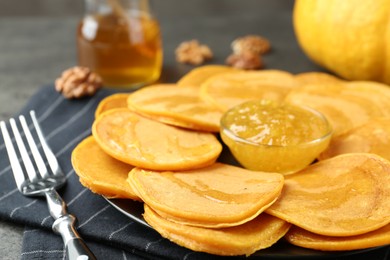 Photo of Tasty pumpkin pancakes with honey and jam on table, closeup