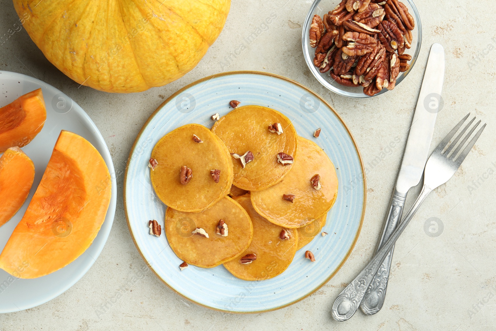 Photo of Tasty pumpkin pancakes with nuts served on light grey table, flat lay