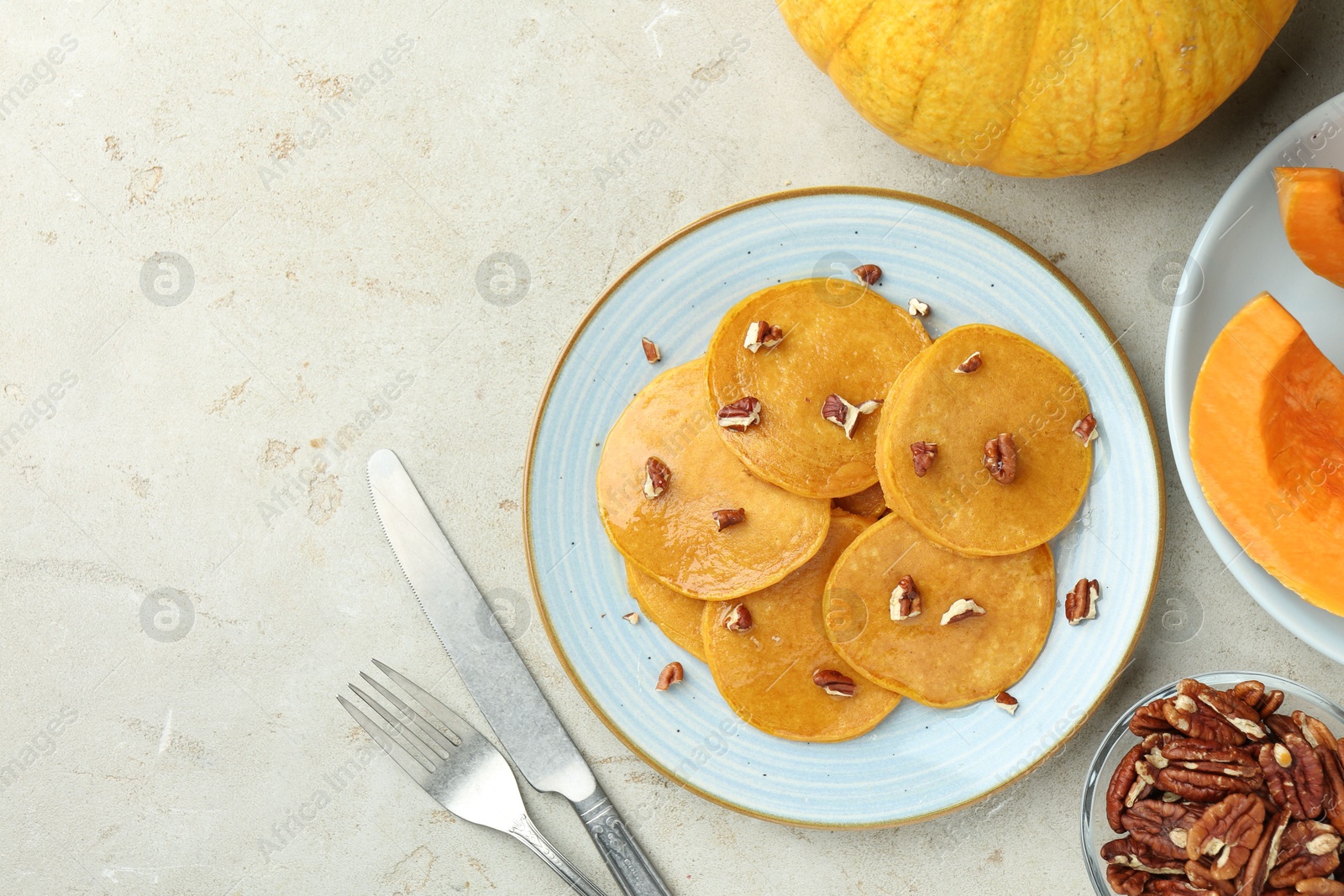 Photo of Tasty pumpkin pancakes with nuts served on light grey table, flat lay. Space for text