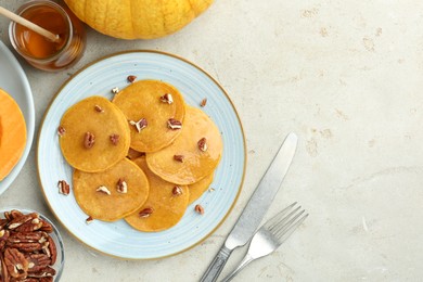 Photo of Tasty pumpkin pancakes with nuts and honey served on light grey table, flat lay. Space for text