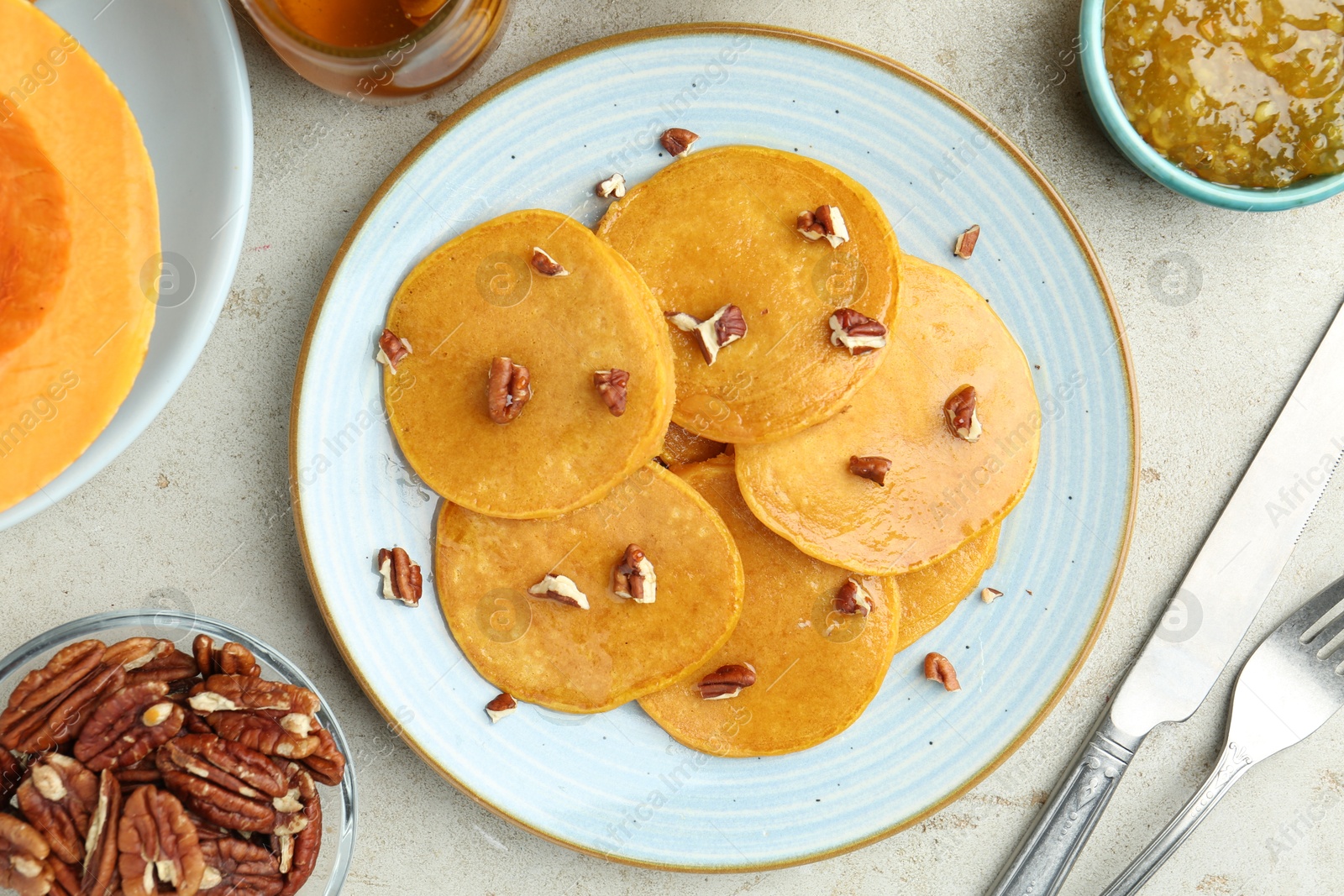 Photo of Tasty pumpkin pancakes with nuts served on light grey table, flat lay