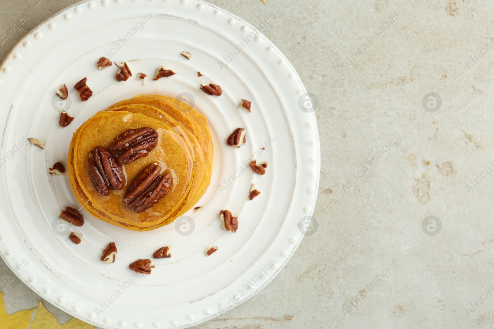 Photo of Tasty pumpkin pancakes with nuts and honey on light grey table, top view. Space for text