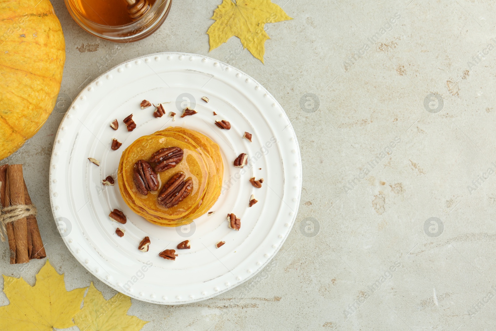 Photo of Tasty pumpkin pancakes with nuts and honey served on light grey table, flat lay. Space for text