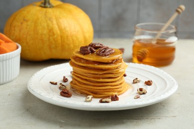 Photo of Tasty pumpkin pancakes with nuts and honey on light grey table, closeup