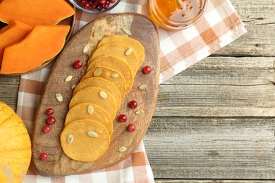 Photo of Tasty pumpkin pancakes with seeds, cranberries and honey on wooden table, flat lay. Space for text