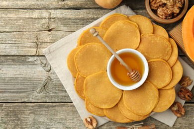 Photo of Tasty pumpkin pancakes, honey and walnuts on wooden table, top view. Space for text