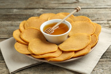 Photo of Tasty pumpkin pancakes and honey on wooden table, closeup