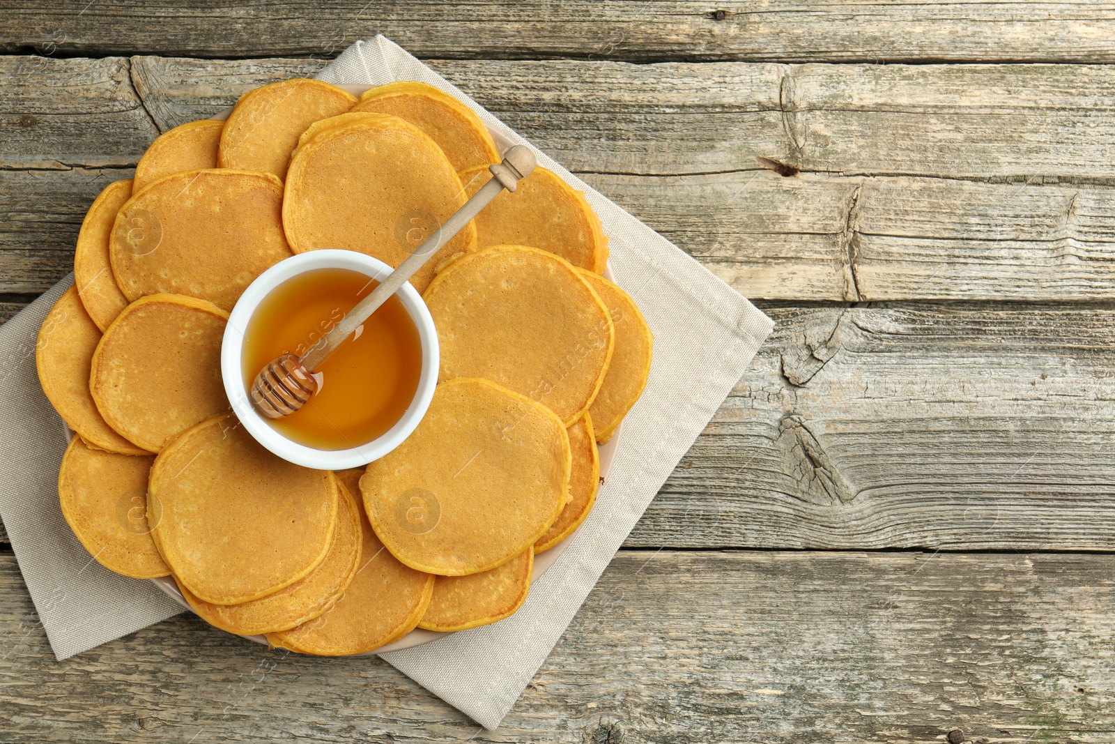 Photo of Tasty pumpkin pancakes and honey on wooden table, top view. Space for text