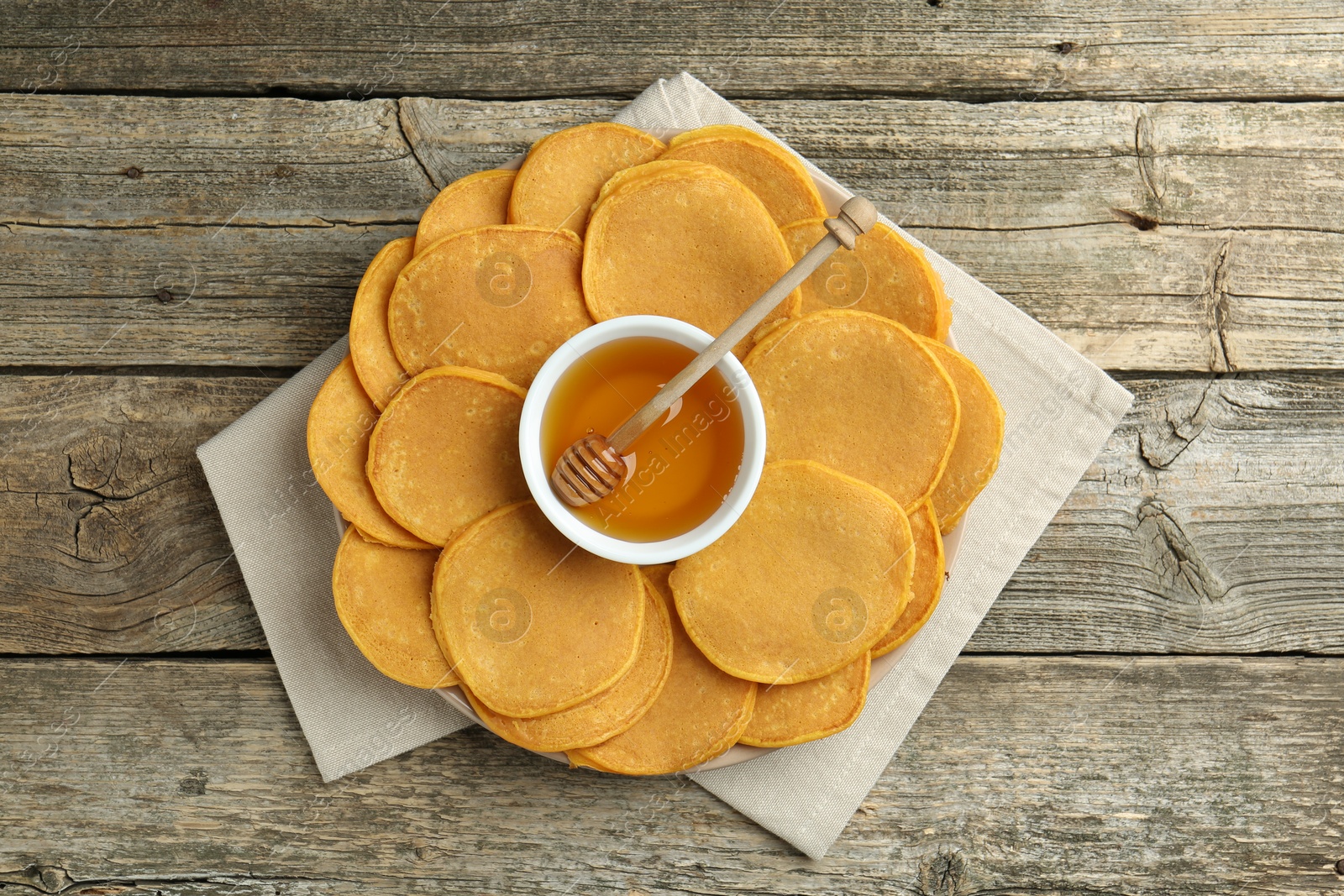 Photo of Tasty pumpkin pancakes and honey on wooden table, top view