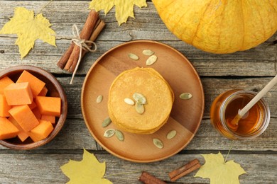 Photo of Tasty pumpkin pancakes with seeds served on wooden table, flat lay