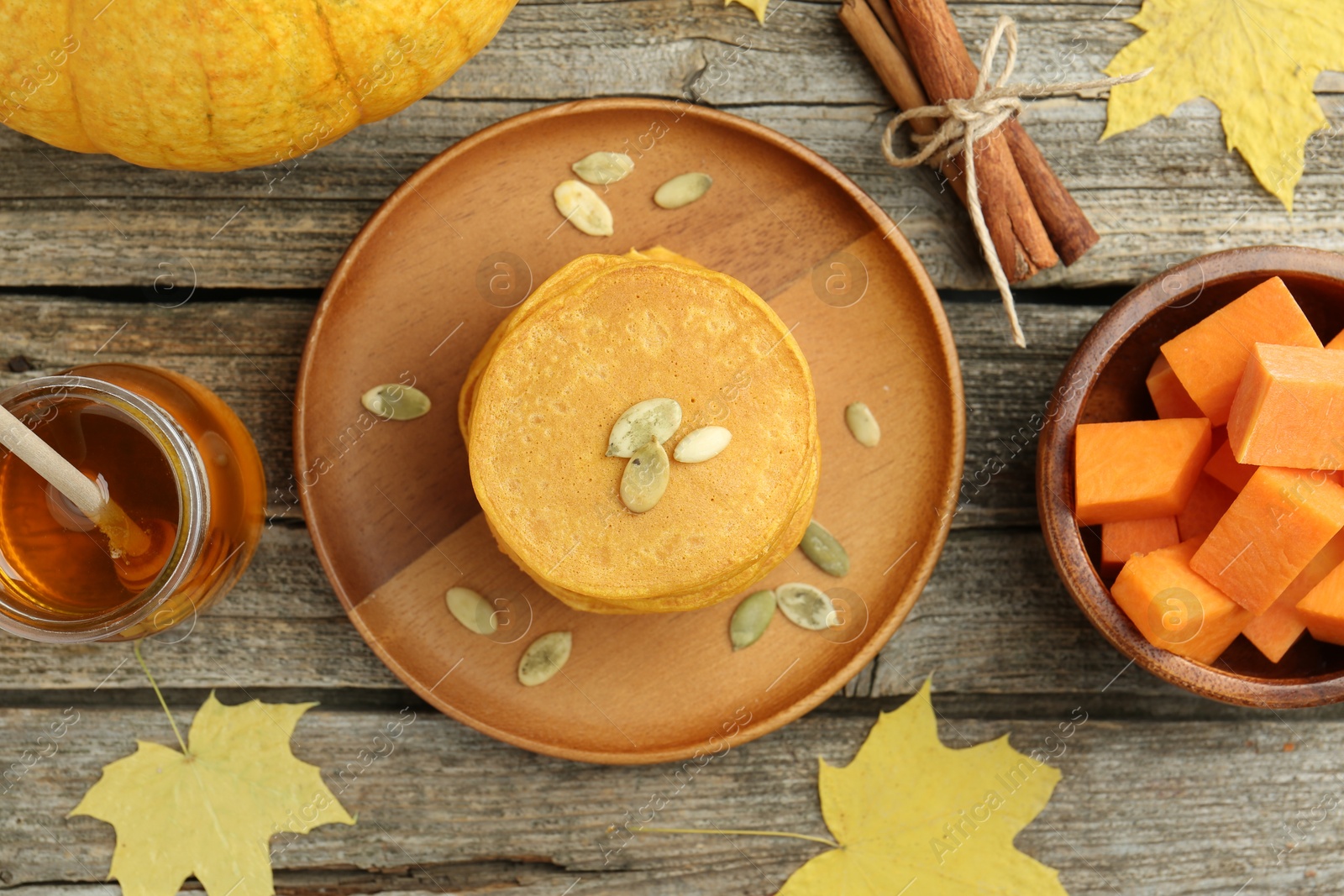 Photo of Tasty pumpkin pancakes with seeds served on wooden table, flat lay