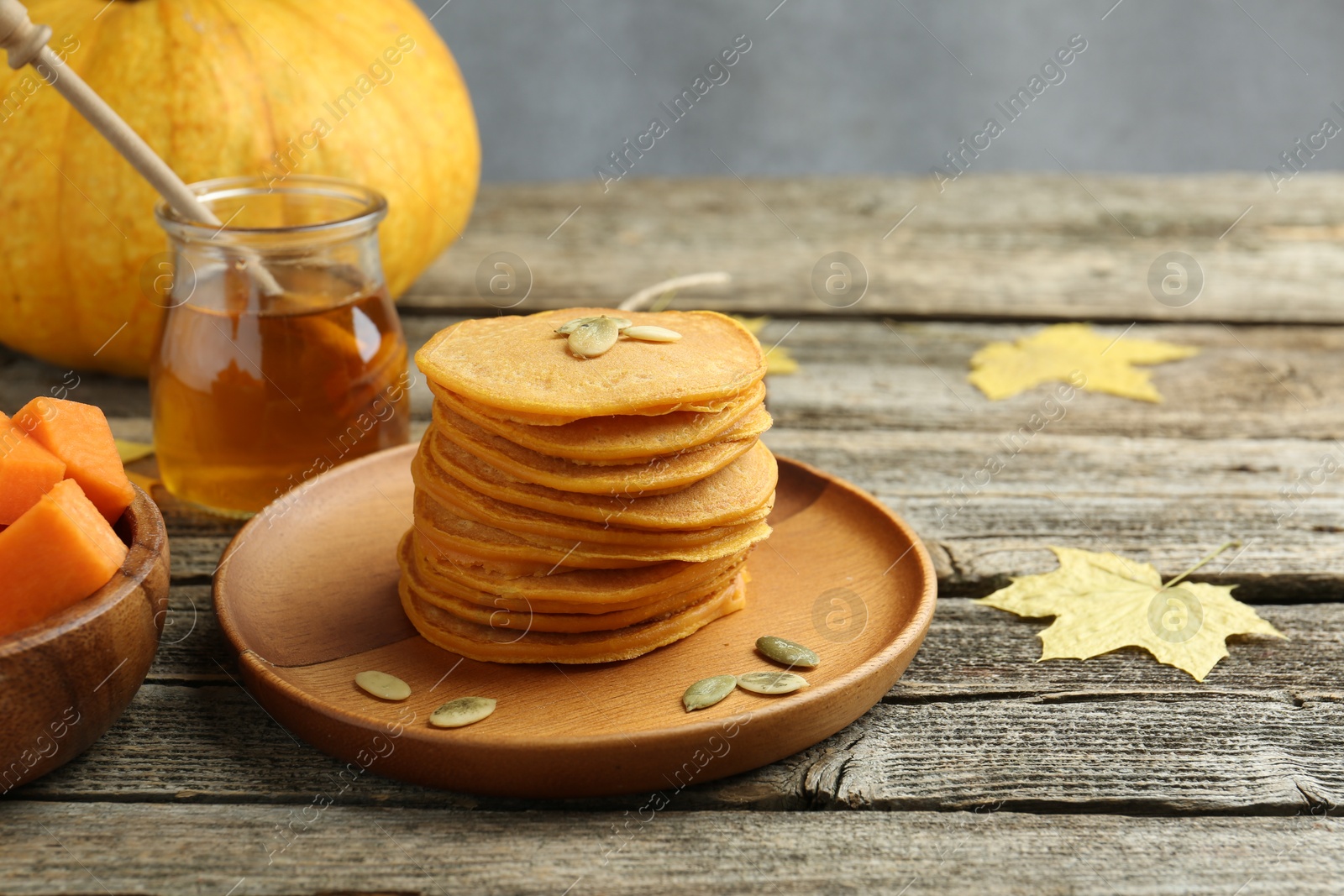 Photo of Tasty pumpkin pancakes with seeds served on wooden table