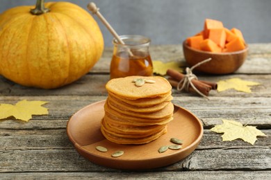 Photo of Tasty pumpkin pancakes with seeds served on wooden table