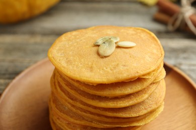 Photo of Tasty pumpkin pancakes with seeds on table, closeup