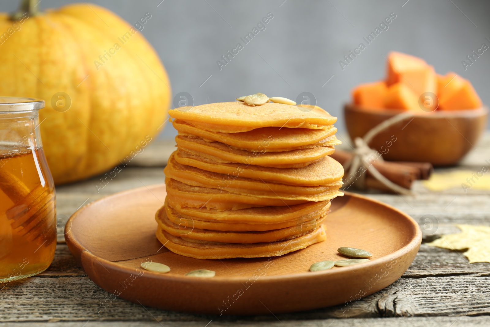 Photo of Tasty pumpkin pancakes with seeds served on wooden table, closeup