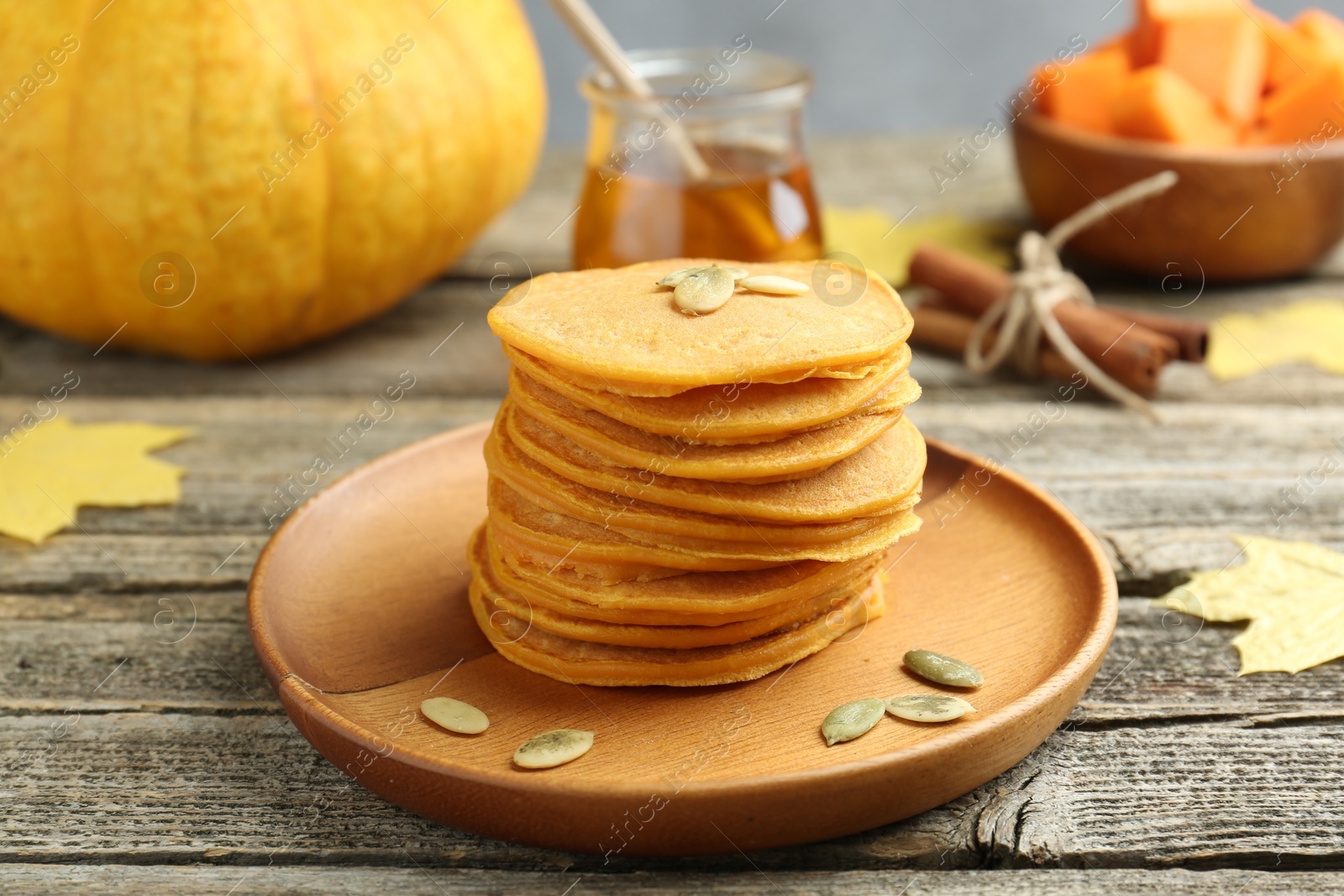 Photo of Tasty pumpkin pancakes with seeds served on wooden table, closeup