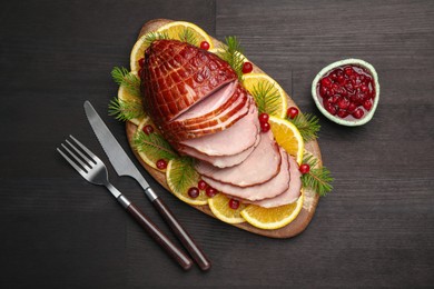 Photo of Tasty baked ham served on black wooden table, flat lay