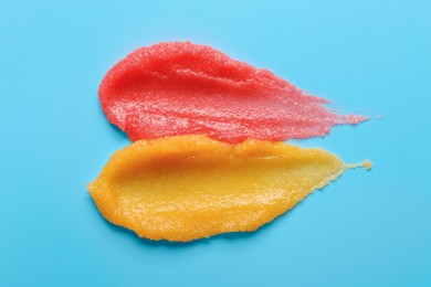 Photo of Smears of different body scrubs on light blue background, top view