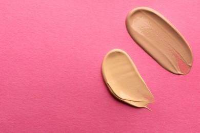 Photo of Foundation on pink background, top view with space for text. Smears of cosmetic product