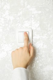 Photo of Woman turning light switch on, closeup view