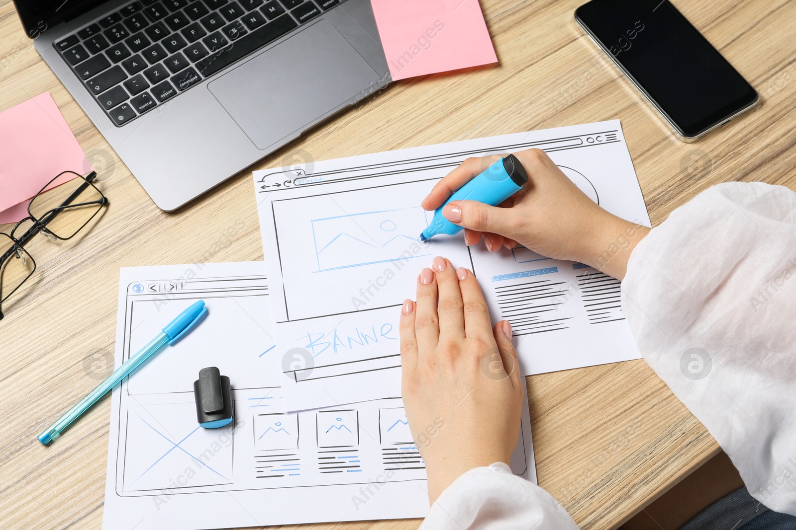 Photo of Website designer creating wireframe on paper with highlighter at wooden table, above view