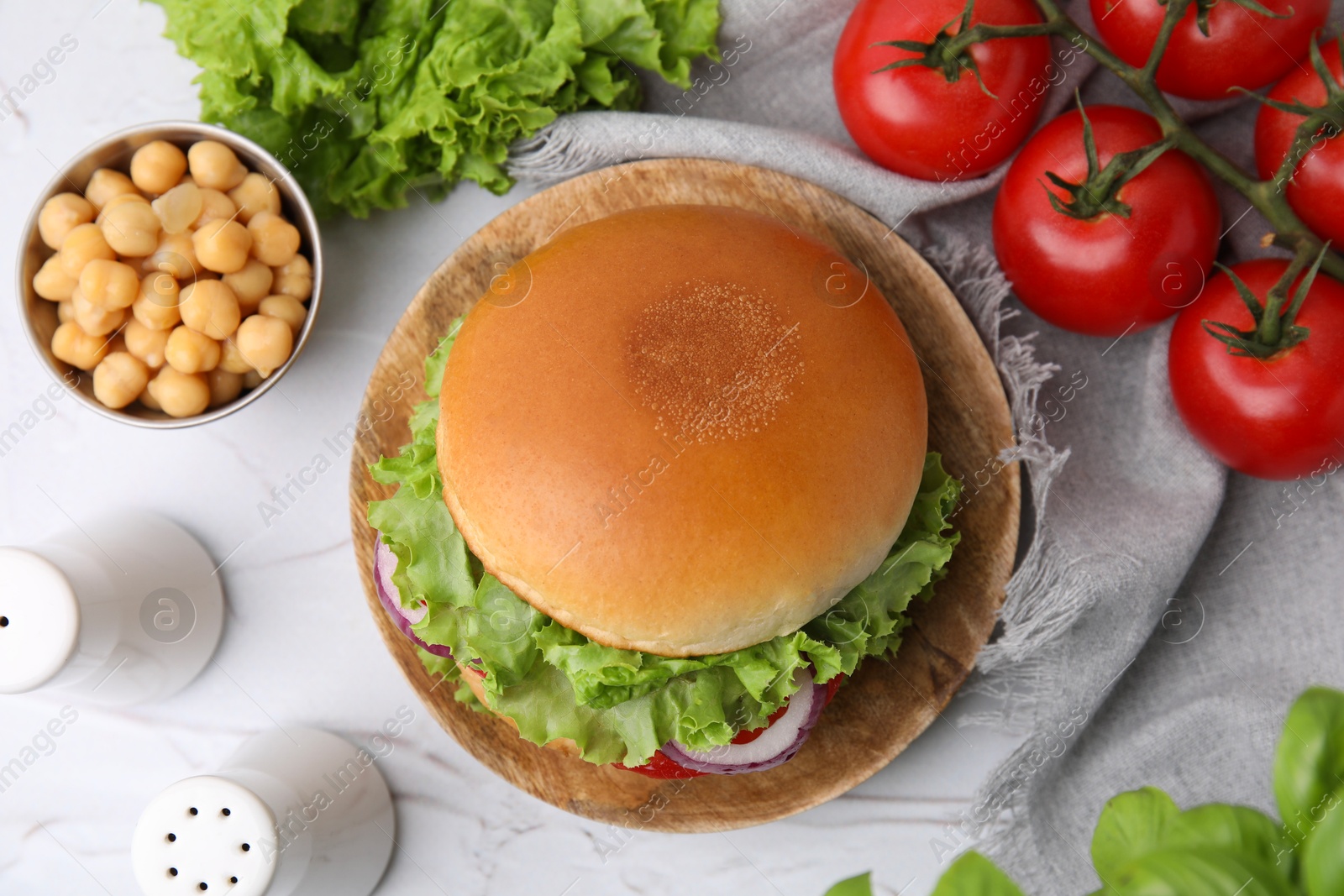 Photo of Delicious vegetarian burger with chickpea cutlet and ingredients on white textured table, flat lay