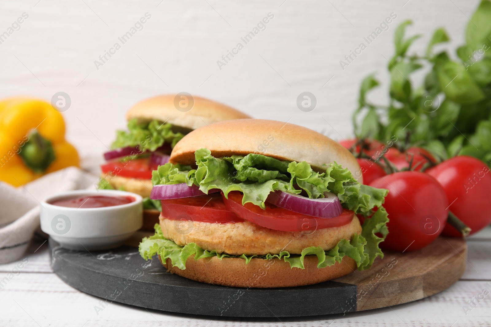 Photo of Delicious vegetarian burgers with chickpea cutlets, ingredients and sauce on white table, closeup