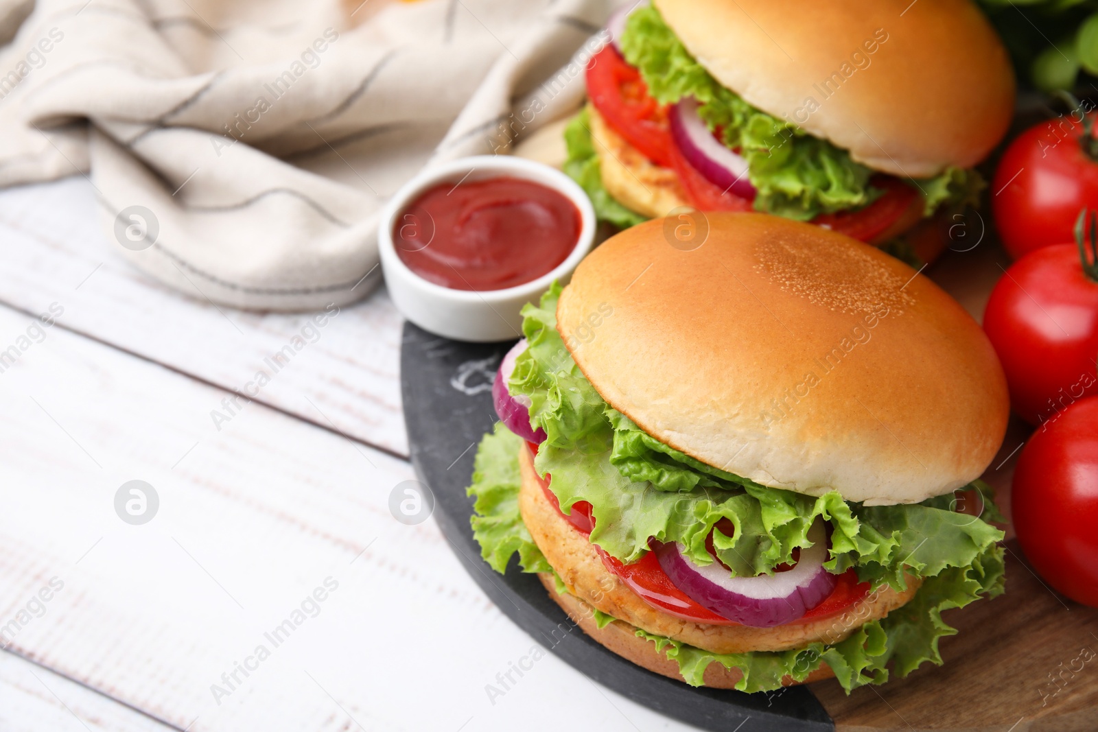 Photo of Delicious vegetarian burgers with chickpea cutlets, tomatoes and sauce on white wooden table, closeup. Space for text