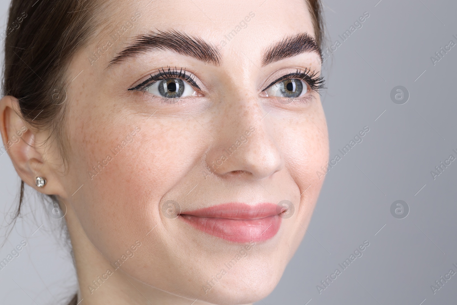 Photo of Woman after brow lamination procedure on grey background, closeup