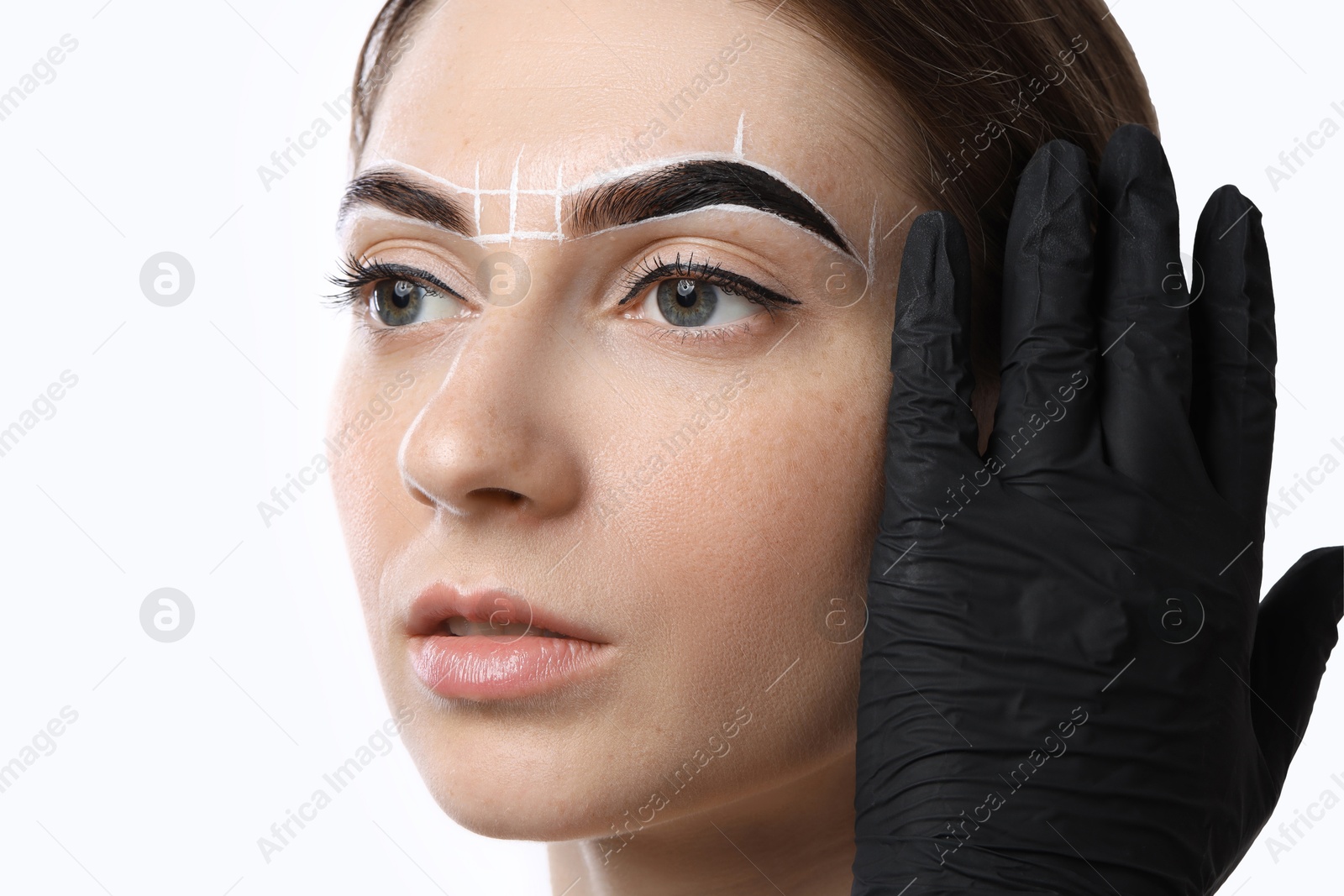 Photo of Young woman undergoing henna eyebrows dyeing on white background, closeup