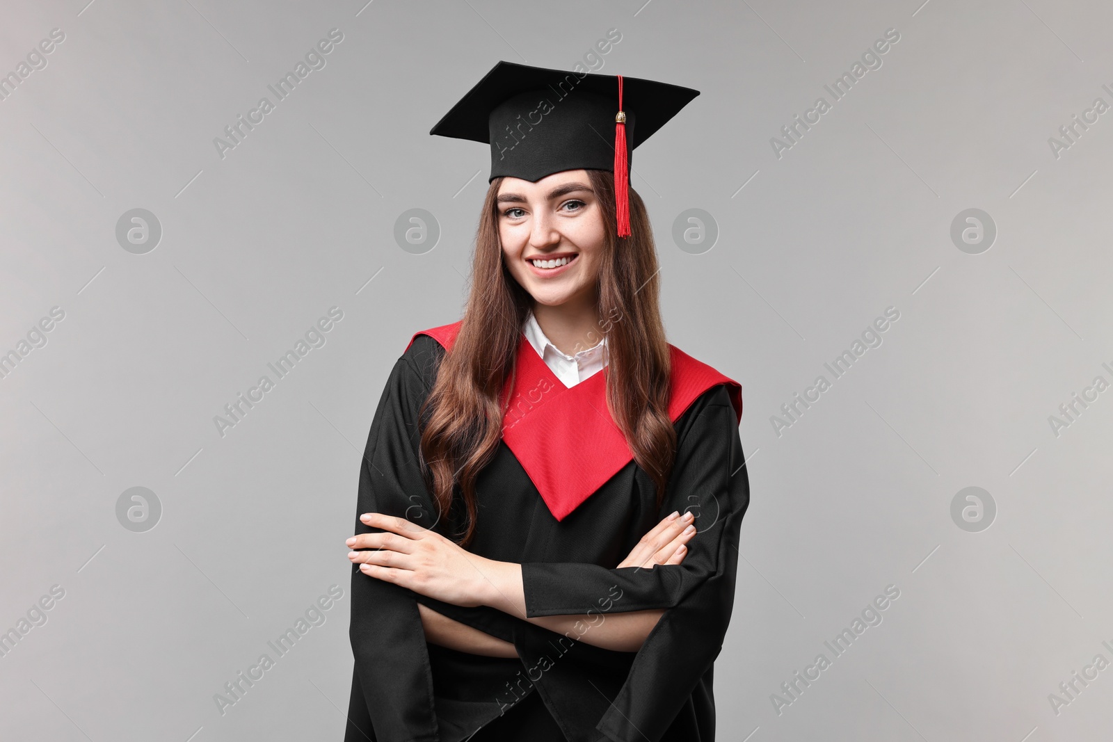 Photo of Happy student with crossed arms after graduation on grey background