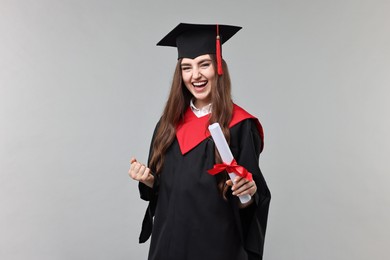 Photo of Happy student with diploma after graduation on grey background