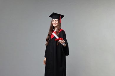 Photo of Happy student with diploma after graduation on grey background