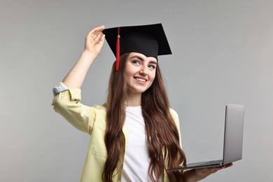 Photo of Happy student with laptop after graduation on grey background