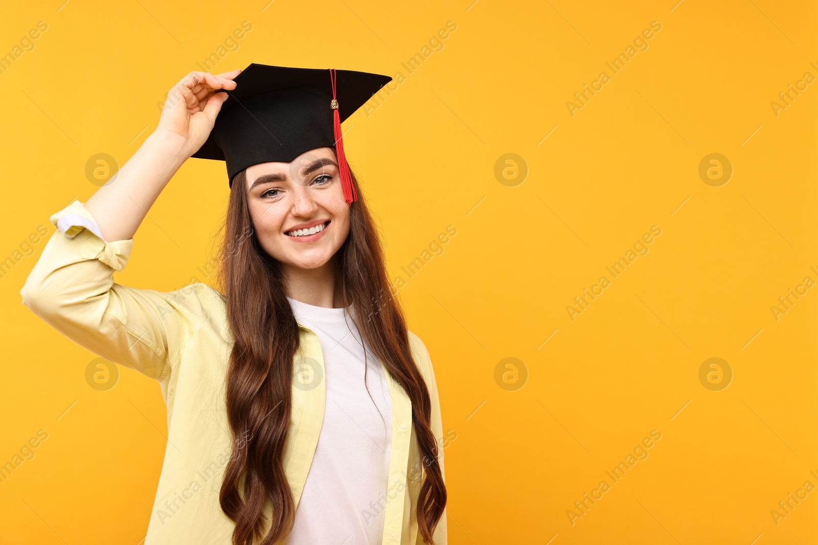 Photo of Happy student after graduation on orange background. Space for text