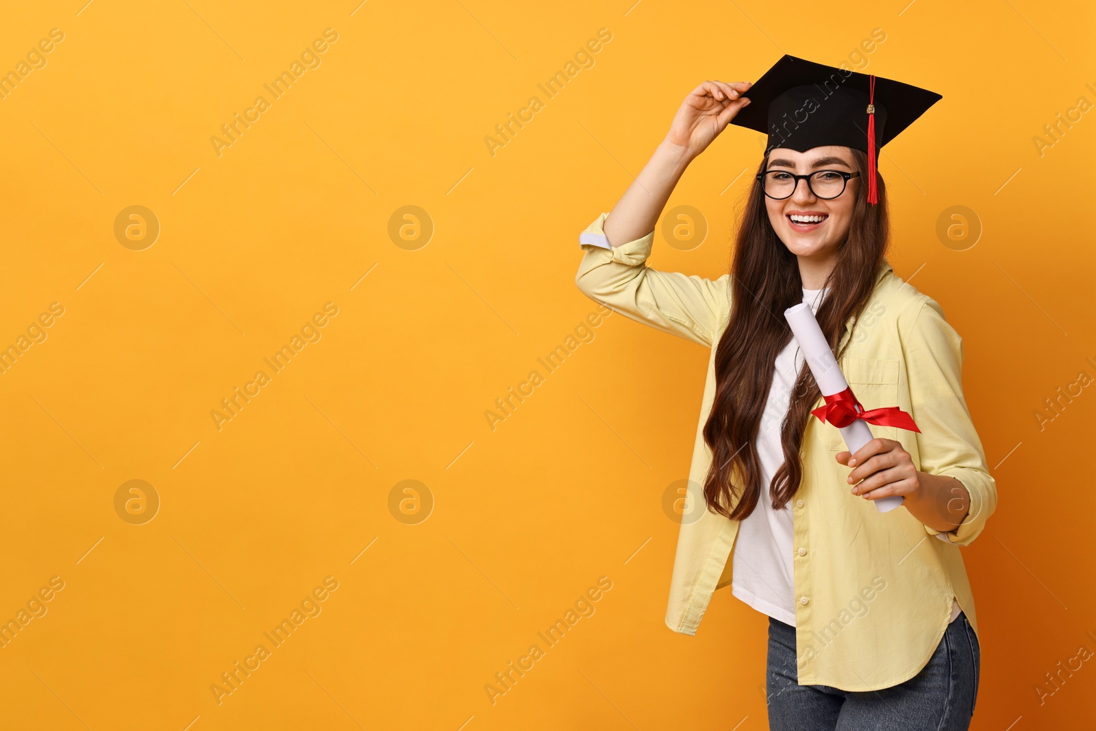 Photo of Happy student with diploma after graduation on orange background. Space for text