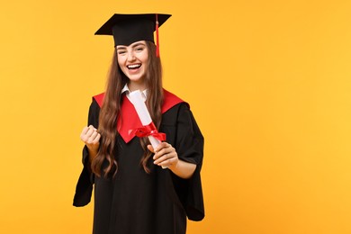 Photo of Happy student with diploma after graduation on orange background. Space for text