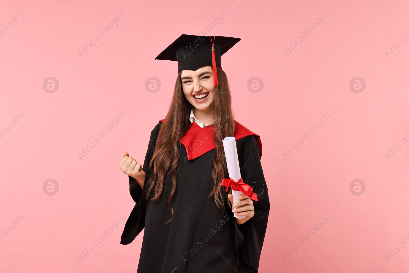 Photo of Happy student with diploma after graduation on pink background