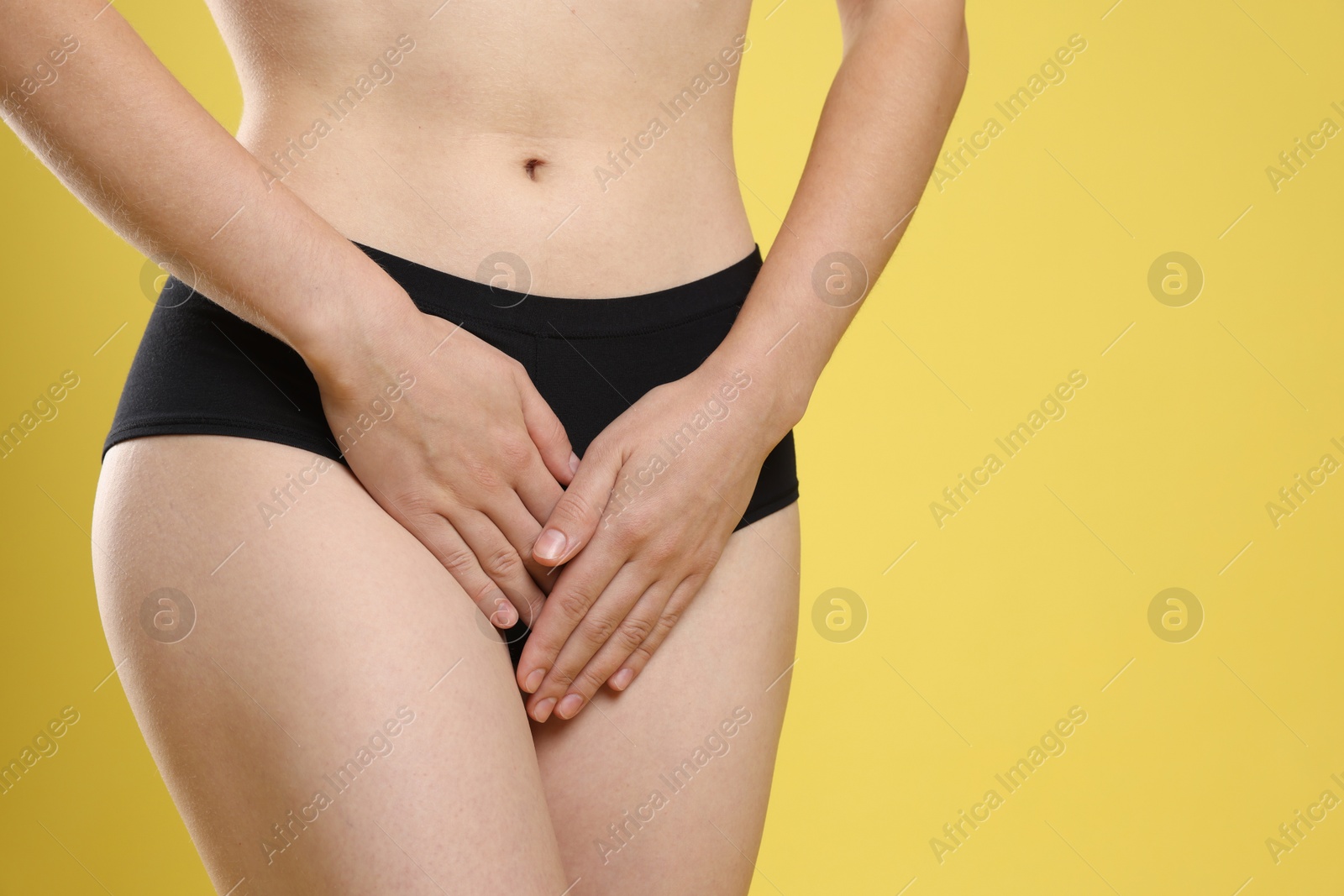 Photo of STD (sexually transmitted disease). Woman suffering from symptoms on yellow background, closeup. Space for text