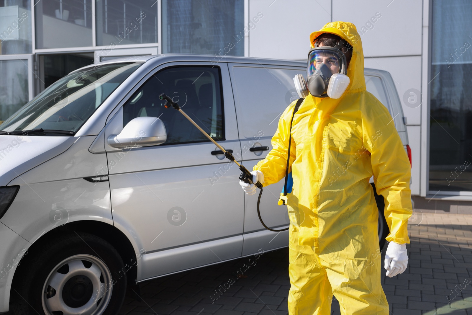 Photo of Pest control worker with spray tank outdoors